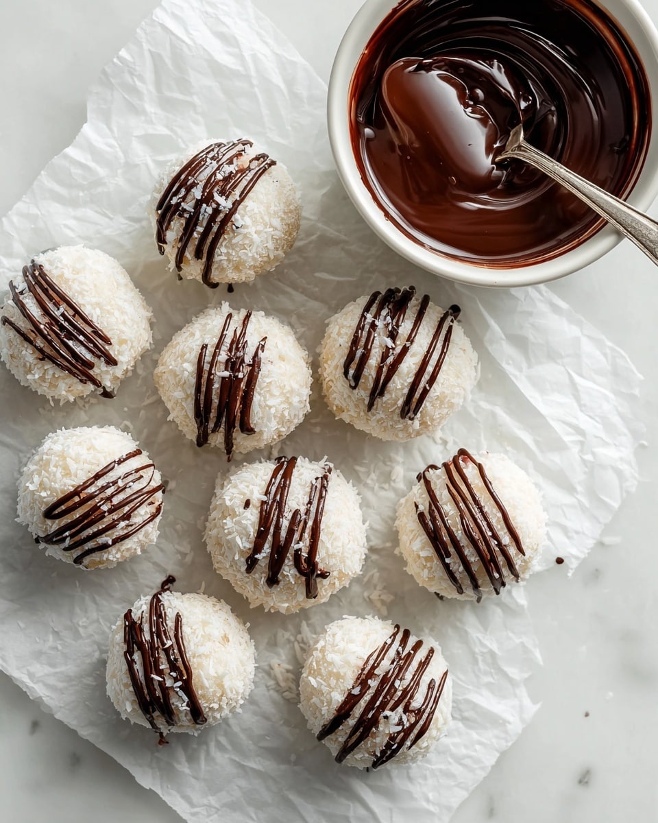 The image shows a group of white coconut-covered round balls, arranged on white parchment paper over a white marbled surface. Each ball has thin, dark brown chocolate strands drizzled evenly across the top and sides. To the upper right side of the balls, there is a white bowl filled with melted dark chocolate with a spoon resting inside, coated with the chocolate. The setting is clean and bright, emphasizing the contrast between the white coconut and the dark chocolate drizzle. photo taken with an iphone --ar 4:5 --v 7