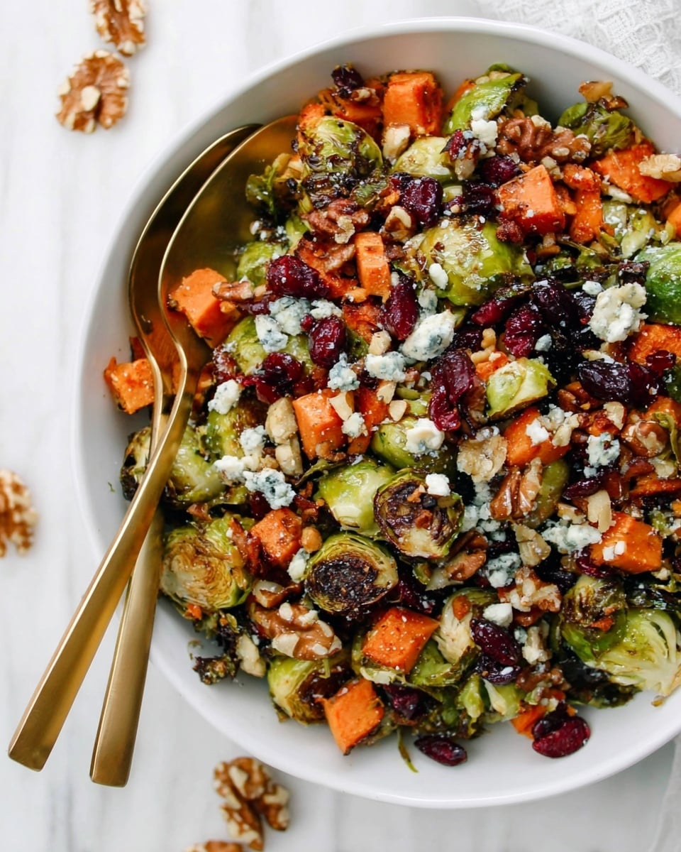 A white bowl filled with a salad made of roasted Brussels sprouts that are browned and charred on the edges, bright orange roasted sweet potato cubes, and scattered dark red dried cranberries. The salad is topped with crumbled white blue cheese and broken pieces of light brown walnuts. Two gold spoons are placed inside the bowl on the left side, partially buried in the mix. The bowl sits on a white marbled surface with a few walnut pieces scattered nearby. photo taken with an iphone --ar 4:5 --v 7