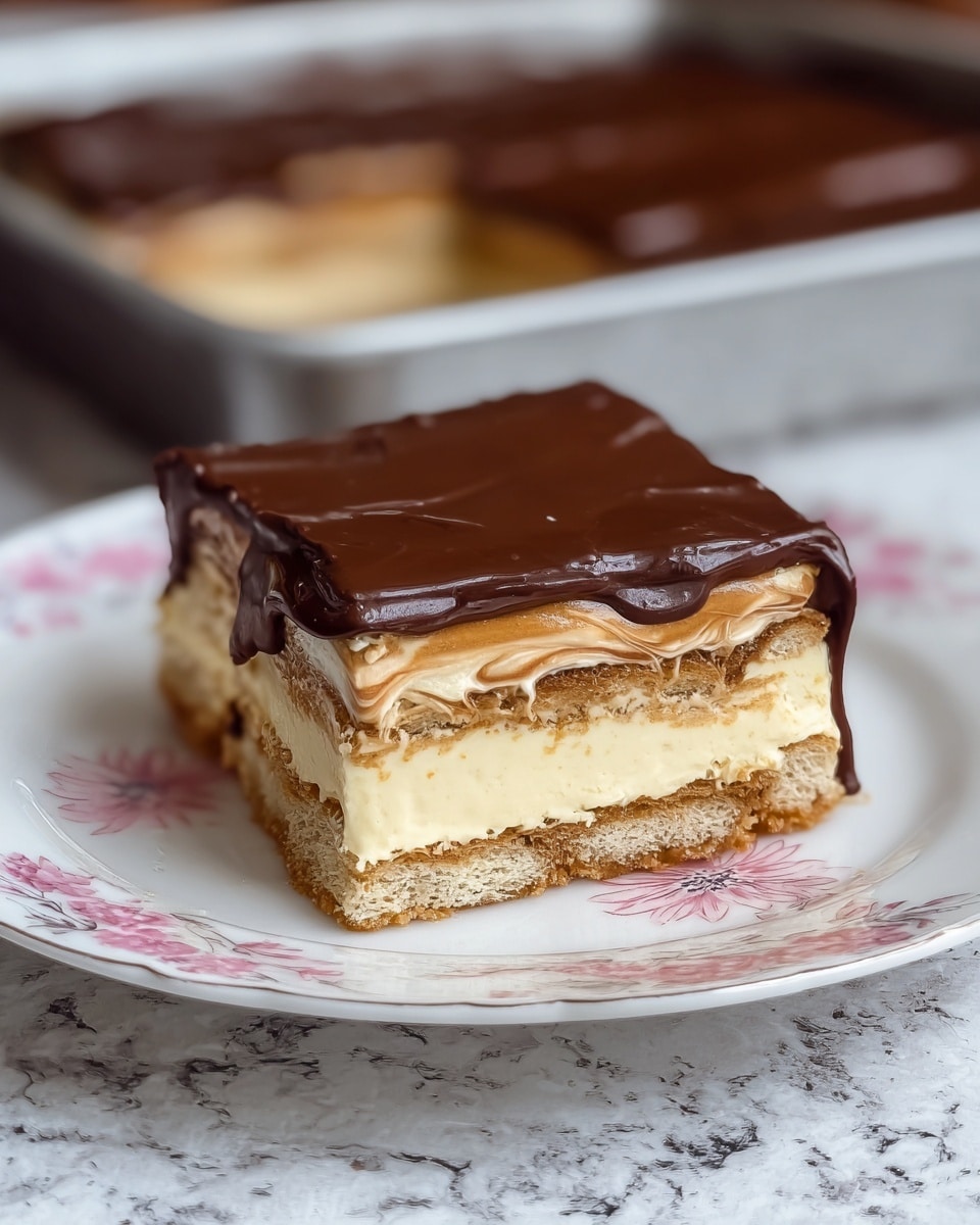 A square piece of layered dessert sits on a white plate with pink floral designs, placed on a white marbled textured surface. The dessert has five distinct layers: starting from the bottom, there is a crumbly light brown biscuit layer, followed by a thick creamy pale yellow layer, then another biscuit layer in light brown, a thinner cream layer with a light brown swirl or caramel pattern, and finally a smooth, glossy dark chocolate layer on top. The edges of the chocolate topping are slightly uneven, and some parts gently drip down the sides. In the background, the rest of the dessert can be seen in a pan with one piece missing. photo taken with an iphone --ar 4:5 --v 7