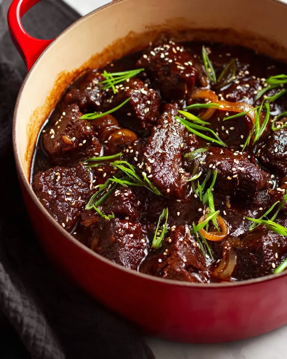 A close-up view of a red pot filled with dark brown beef chunks in rich, thick sauce, each piece glistening and covered with small white sesame seeds. On top of the beef pieces are thin slices of fresh green onions scattered throughout, adding a fresh contrast to the deep dark sauce. Thin cooked onion rings are mixed into the sauce, adding a slight texture variation. The pot sits on a white marbled surface, with a soft black cloth partially visible. photo taken with an iphone --ar 4:5 --v 7