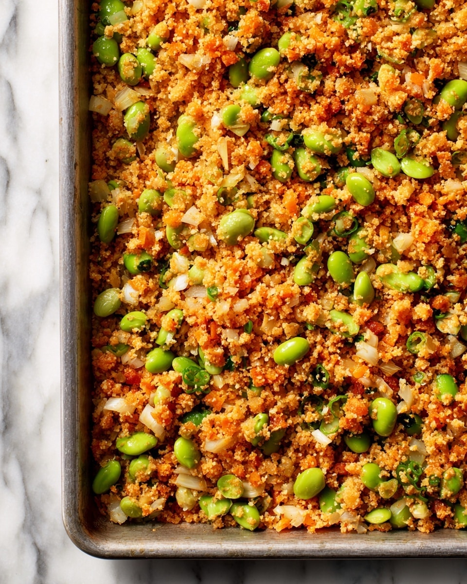 A patterned beige bowl on a white marbled surface holds a dish with two layers: the bottom layer is a mix of cooked brown rice, green edamame beans, and small pieces of cooked vegetables in a reddish sauce, creating a textured and colorful base; on top is a sunny-side-up egg with a soft, white edge and a slightly runny yolk, sprinkled with thinly sliced green onions and white sesame seeds. The bowl rests partly on a blue and white striped cloth. Photo taken with an iphone --ar 4:5 --v 7