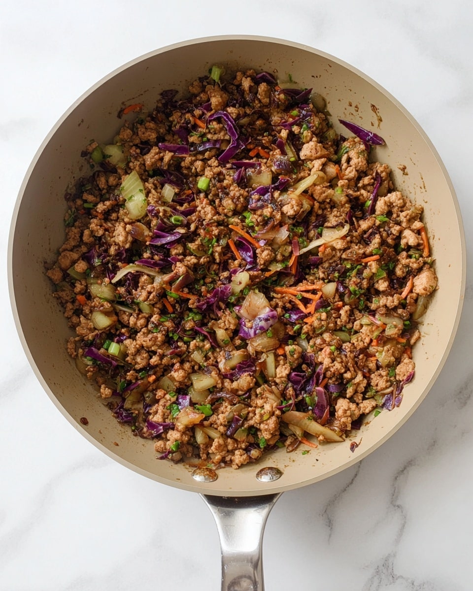 A white bowl filled with a stir-fry dish that has three main layers: a base of cooked ground meat mixed with soft pieces of eggplant, topped with vibrant green chopped spring onions, and finished with white sesame seeds and drizzles of a red sauce adding color contrast. The food is placed on a rough-cut wooden board layered with a burnt orange cloth, next to a pair of wooden chopsticks resting on the edge of the board. The setting is on a white marbled surface and part of a light gray pan with more stir-fry is visible in the background. Photo taken with an iphone --ar 4:5 --v 7