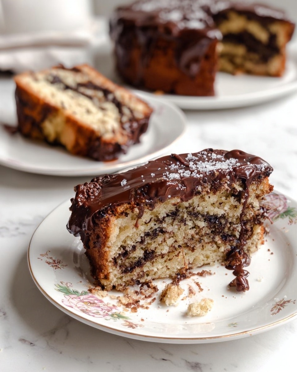 Two thick slices of cake sit on a white plate with floral patterns; the cake has three layers visible—a light brown crumb with dark chocolate swirls inside and a thick layer of smooth, shiny chocolate glaze on top that drips slightly onto the plate, mixing with some crumbs and a bit of white salt flakes sprinkled on the top. In the background, out of focus, two more slices of the same cake rest on another white plate. The setting is on a white marbled surface. Photo taken with an iphone --ar 4:5 --v 7
