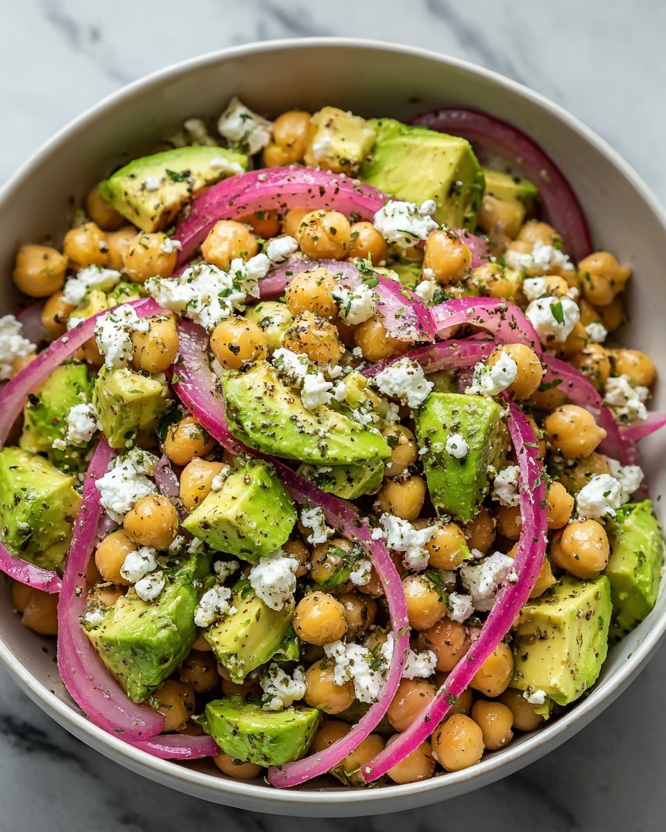 A white bowl filled with a chickpea salad consisting of three main layers: at the bottom, large chunks of bright green avocado with a smooth texture; the middle layer has light golden chickpeas that look soft and round; scattered throughout are thin slices of purple-red pickled onions adding a pop of color. On top, there are small white crumbles of soft cheese and specks of chopped green herbs with a light sprinkling of black pepper. The salad looks fresh and mixed gently, sitting on a white marbled surface. Photo taken with an iphone --ar 4:5 --v 7