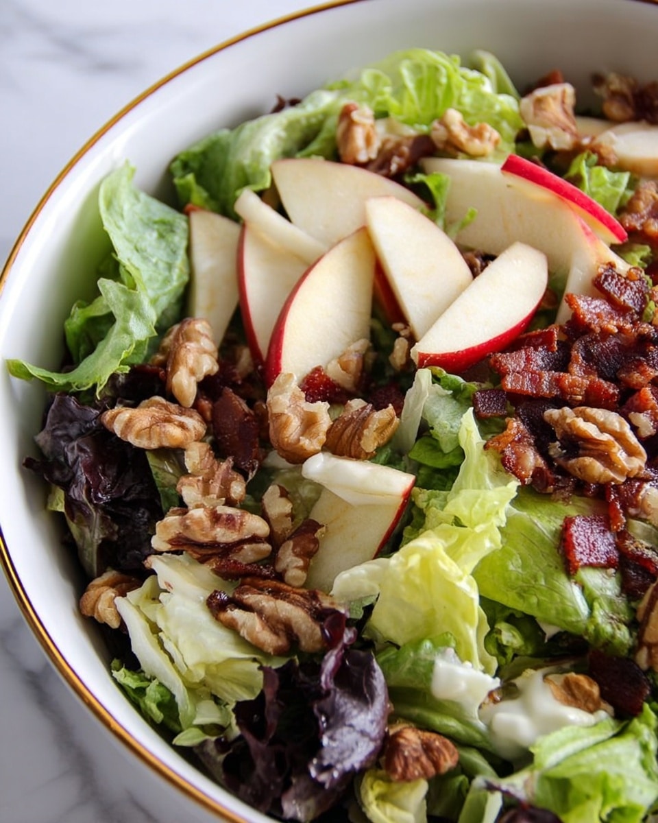 A close-up view of a fresh salad in a white bowl with a gold rim, showing three main layers. The bottom layer is made of green leafy lettuce with light and dark shades, some pieces looking soft and others curly. The middle layer has sliced white and red apple pieces with thin skin and crunchy texture, spread evenly. The top layer includes small chunks of cooked bacon that are dark brown and slightly crispy, and large pieces of walnuts with a rough texture and light brown color scattered throughout. The background is a white marbled surface. Photo taken with an iphone --ar 4:5 --v 7