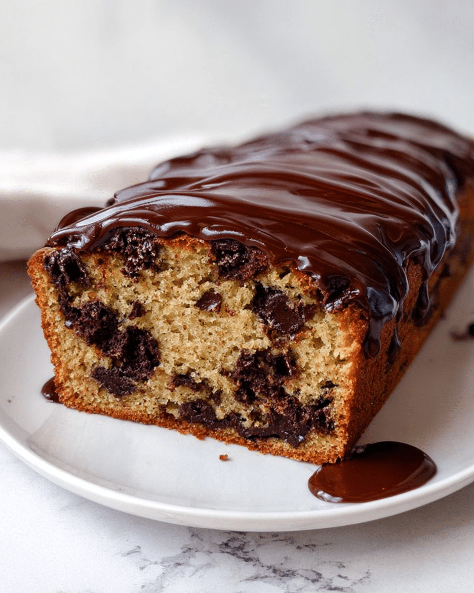 The image shows a loaf cake on a white plate with a white marbled texture background. The cake has one visible layer with a light brown color and dark chocolate chunks distributed inside. The top of the cake is covered with a thick, glossy layer of dark chocolate ganache that slightly drips down the sides and pools a little on the plate. The texture of the cake looks soft and moist, and the chocolate topping adds a smooth, shiny finish. photo taken with an iphone --ar 4:5 --v 7