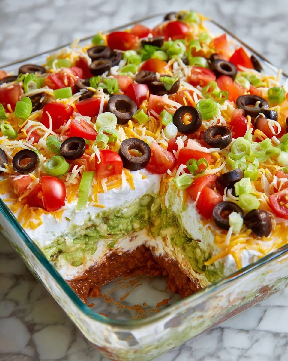 A square glass dish holds a multi-layered dip sitting on a white marbled surface, with a corner section missing, showing the inside layers. The bottom layer is a reddish-brown, likely refried beans, followed by a chunky green layer of guacamole. Above this is a white creamy layer, possibly sour cream, topped with a mix of shredded yellow and white cheese. The top is decorated with chopped bright red tomatoes, black olive slices, and small pieces of green onion, giving it a colorful and fresh look. Photo taken with an iphone --ar 4:5 --v 7